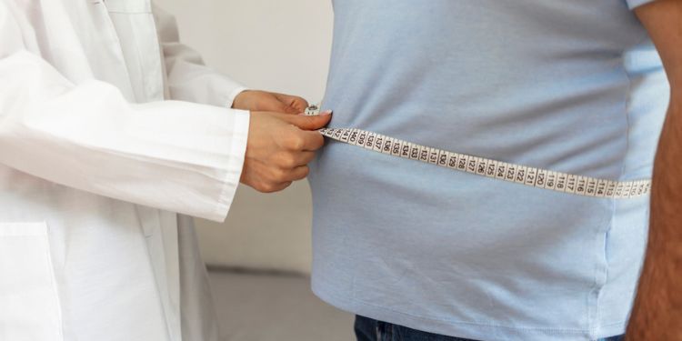 Medico che misura addome per valutare intervento di chirurgia bariatrica